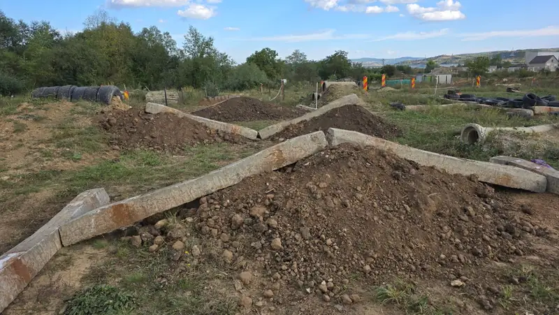 Grinzi de beton asezate in V peste movile de pamant, cu anvelope si tuburi de beton in fundal