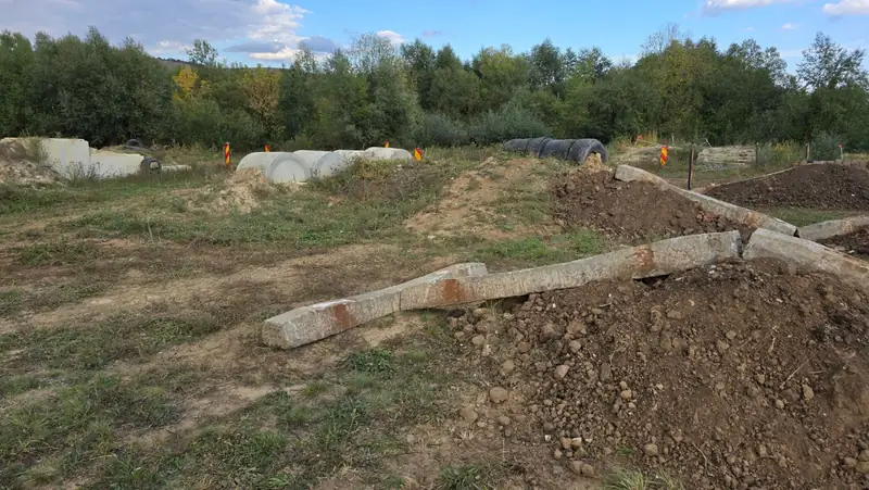 Grinzi de beton pe movile de pamant, cu tuburi de beton si anvelope in fundal